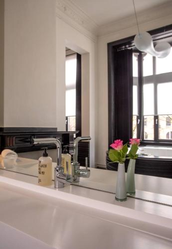 a bathroom with a sink with vases and a mirror at B&B Suites FEEK in Antwerp