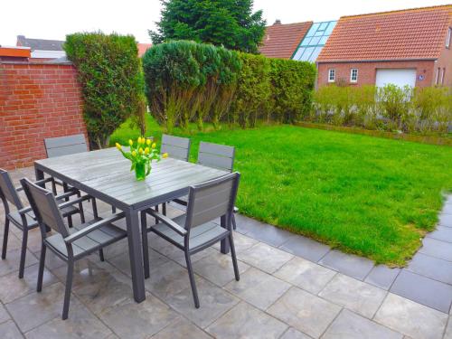 une table et des chaises sur une terrasse avec une pelouse dans l'établissement Holiday Home Nilles by Interhome, à Norddeich