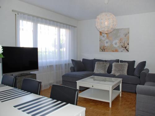 a living room with a blue couch and a tv at Apartment Large Suite-20 by Interhome in Ascona
