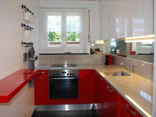 a kitchen with red cabinets and a stove and a sink at Apartment Large Suite-20 by Interhome in Ascona