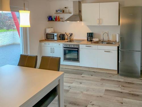 La cuisine est équipée de placards blancs et d'un réfrigérateur en acier inoxydable. dans l'établissement Apartment Seeteufel by Interhome, à Norddeich