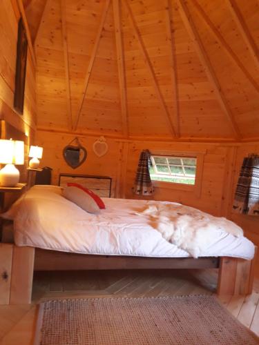 ein Schlafzimmer mit einem Bett in einem Holzzimmer in der Unterkunft Le Kota Montagne in Les Poulières