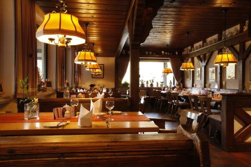 ein Restaurant mit Holztischen, Stühlen und Lampen in der Unterkunft Flörsbacher Hof in Flörsbachtal