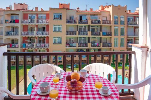 a table with a bowl of fruit on a balcony with a building at Aptos. Comte D´Empuries in Empuriabrava