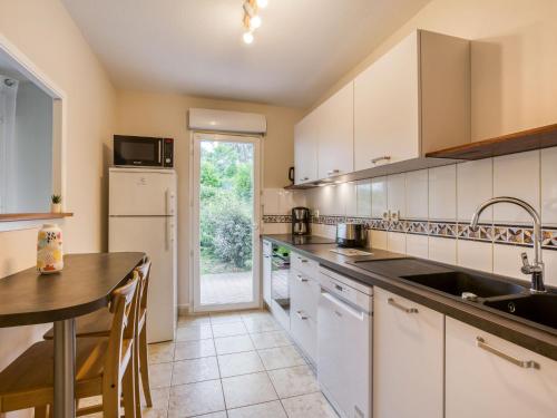 a kitchen with white cabinets and a sink and a table at Apartment Tassigny by Interhome in Capbreton