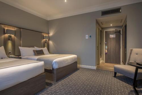 a hotel room with two beds and a chair at Crowne Plaza - Sheffield by IHG in Sheffield