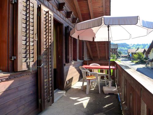 une terrasse avec une table et un parasol dans l'établissement Apartment Chalet Burgfeld by Interhome, à Beatenberg