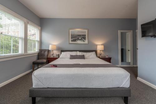 a bedroom with a large bed and two windows at Homestead Inn in New Milford