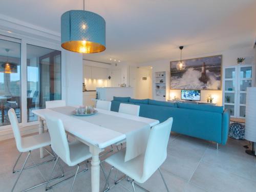 a dining room with a table and a blue couch at Apartment PURA VIDA by Interhome in Bredene