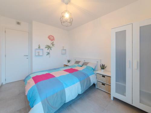 a bedroom with a colorful bed and a dresser at Apartment PURA VIDA by Interhome in Bredene