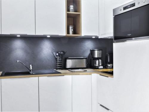 une cuisine blanche avec un évier et un micro-ondes dans l'établissement Apartment L'Espace Montagne-16 by Interhome, à Chamonix-Mont-Blanc