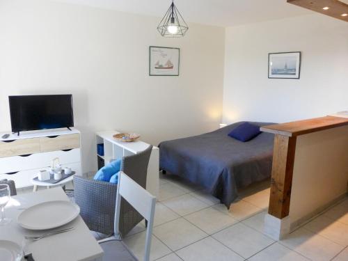 een slaapkamer met een bed en een tafel en een televisie bij Apartment Le Capricorne by Interhome in Cabourg