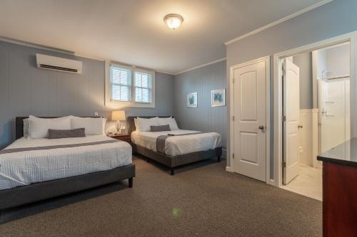 a bedroom with two beds and a window and a door at Homestead Inn in New Milford