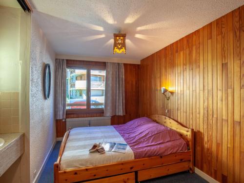 een slaapkamer met een bed met een houten muur bij Apartment Les Grandes Balmes I et II - Le Lac-10 by Interhome in Tignes