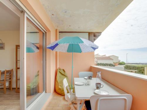 un balcon avec une table et un parasol dans l'établissement Studio La Dune-6 by Interhome, à Capbreton