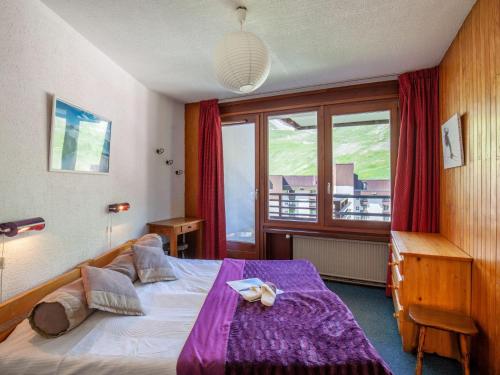 - une chambre avec un lit doté de draps violets et une fenêtre dans l'établissement Apartment Le Curling B - Val Claret-40 by Interhome, à Tignes