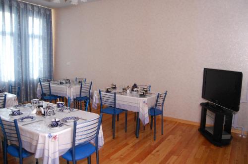 a dining room with tables and chairs with a tv at Jahongir B&B Tashkent in Tashkent