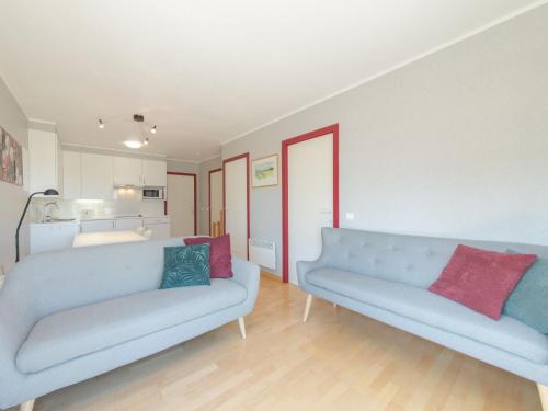 a living room with two blue couches and a kitchen at Apartment Cannes 208 with balcony by Interhome in Bredene