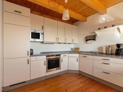 cocina con armarios blancos y techo de madera en Apartment Pistenblick-2 by Interhome, en Hochrindl