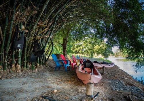 a group of chairs and a boat next to the water at Gardenia Springs - La Finca Buritaca in Buritaca