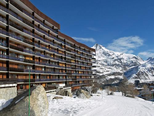 un grand bâtiment avec une montagne enneigée en arrière-plan dans l'établissement Apartment Le Bec Rouge - Le Lac-7 by Interhome, à Tignes