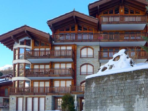 een groot appartementencomplex met sneeuw op de grond bij Apartment Shangri La by Interhome in Zermatt