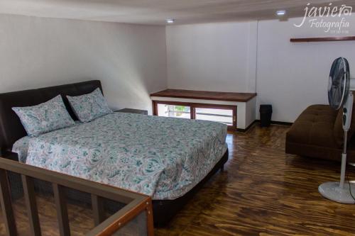 a bedroom with a bed and a chair and a fan at LOFTS en Cuernavaca con alberca climatizada in Cuernavaca