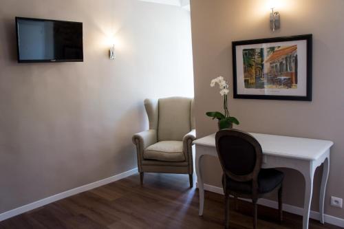 een kamer met een bureau, 2 stoelen en een televisie bij Hotel de France in Saint-Maximin-la-Sainte-Baume