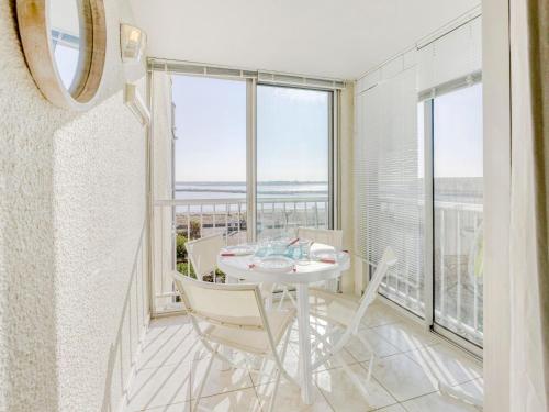 une salle à manger avec une table, des chaises et des fenêtres dans l'établissement Apartment Les Portes de la Plage by Interhome, à Gruissan
