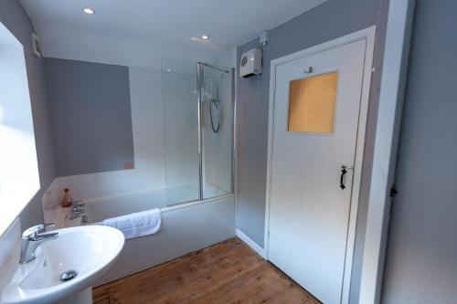 a white bathroom with a shower and a sink at Aberdulas Cottage in the Dyfi Valley Wales in Machynlleth