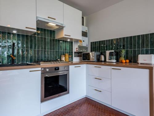 a kitchen with white cabinets and green tiles at Studio Village de Légenèse-4 by Interhome in Carnac