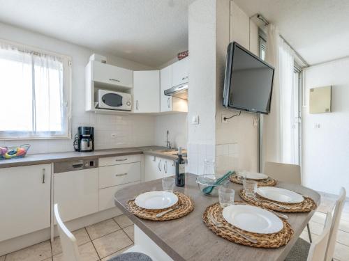 d'une cuisine avec une table et deux plaques blanches. dans l'établissement Apartment Les Capounades-6 by Interhome, à Narbonne-Plage