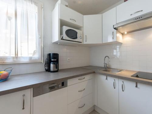 une cuisine avec des armoires blanches et un micro-ondes dans l'établissement Apartment Les Capounades-6 by Interhome, à Narbonne-Plage