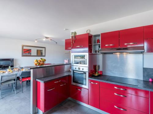 une cuisine rouge avec des placards rouges et une table dans l'établissement Apartment Les terrasses di Fiori by Interhome, à Porto-Vecchio