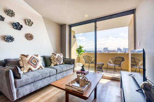 a living room with a couch and a large window at ULIV Luxe Apartments Polanco in Mexico City