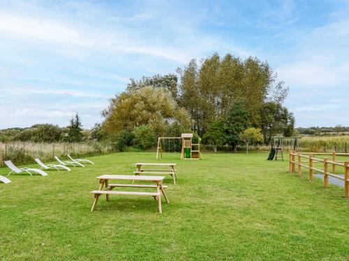 - un groupe de tables de pique-nique et de chaises dans un parc dans l'établissement Holiday Home L'oyat by Interhome, à Pirou