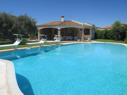 una grande piscina con sedie e una casa di Holiday Home Rei Sole - REI308 by Interhome a Costa Rei