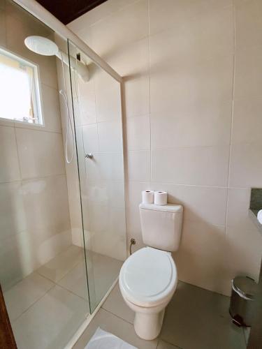 a bathroom with a toilet and a glass shower at Pousada Cabanas Kaia Lua in Praia do Rosa