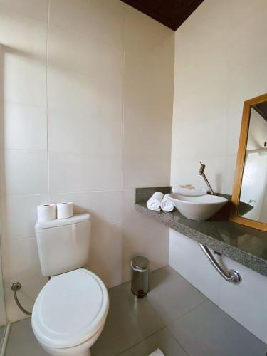 a white bathroom with a toilet and a sink at Pousada Cabanas Kaia Lua in Praia do Rosa