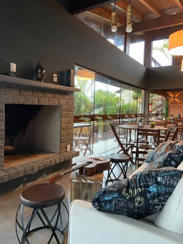 a living room with a fireplace and tables and chairs at Pousada Cabanas Kaia Lua in Praia do Rosa