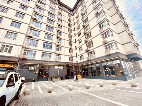 a large building with a parking lot in front of it at DeLight Apartments in Boryspilʼ