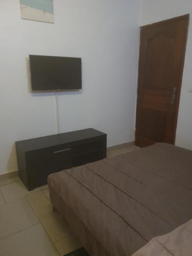 a bedroom with two beds and a television on the wall at Appart Sly Abidjan in Cocody