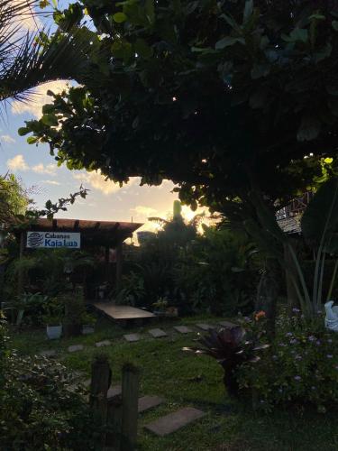 a view of a garden with a tree and a building at Pousada Cabanas Kaia Lua in Praia do Rosa