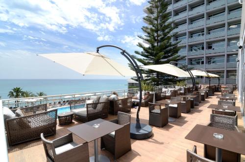 a patio area with tables, chairs and umbrellas at Medplaya Hotel Riviera - Adults Only in Benalmádena