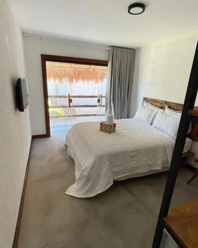 une chambre avec un lit et une grande fenêtre dans l'établissement Casa Rústica com Rooftop e 2 Piscinas - 100mts do Mar - Rota dos Milagres, à São Miguel dos Milagres
