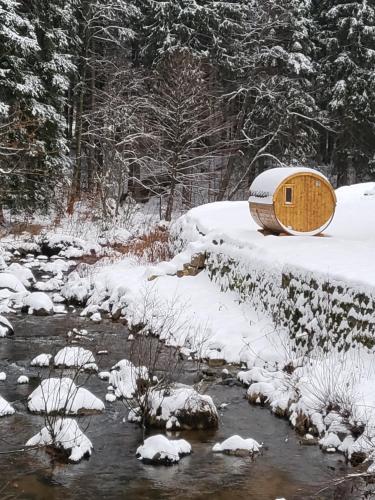 a wooden tub sitting next to a stream in the snow at HORSKÝ PENZION U SPLAVU in Josefuv dul