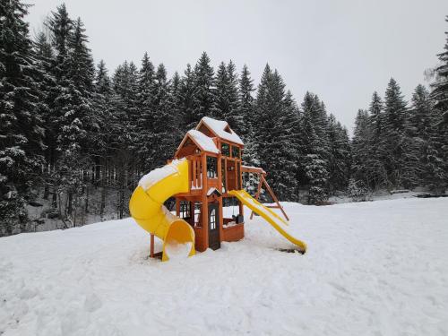 a playground in the snow with trees in the background at HORSKÝ PENZION U SPLAVU in Josefuv dul