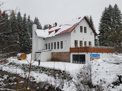 a white house with snow on top of it at HORSKÝ PENZION U SPLAVU in Josefuv dul