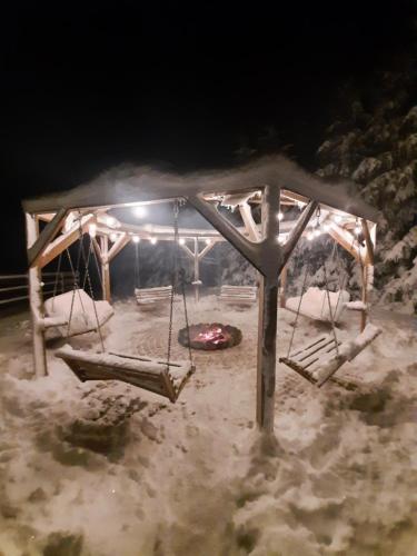 a swing set in the snow at night at Gilė -'Virš Ąžuolų' - Forest SPA - Horses - Lake - Chalet in Paplatelė
