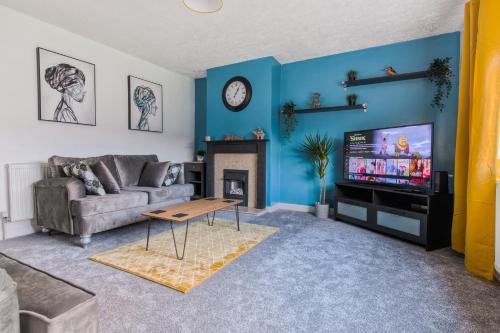 a living room with a couch and a tv at Rookwood house - spacious home with free parking - Short Stay Leeds in Killingbeck